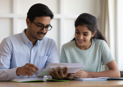 Photorealistic image of Indian parent and teenage child discussing college planning documents against a clean white background